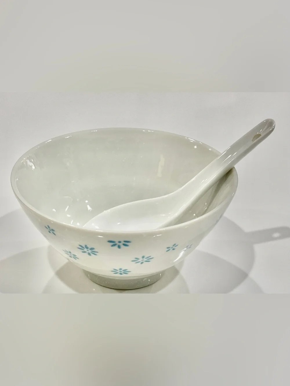 White Ceramic Bowl with Blue Floral Motif on Exterior and Matching Spoon